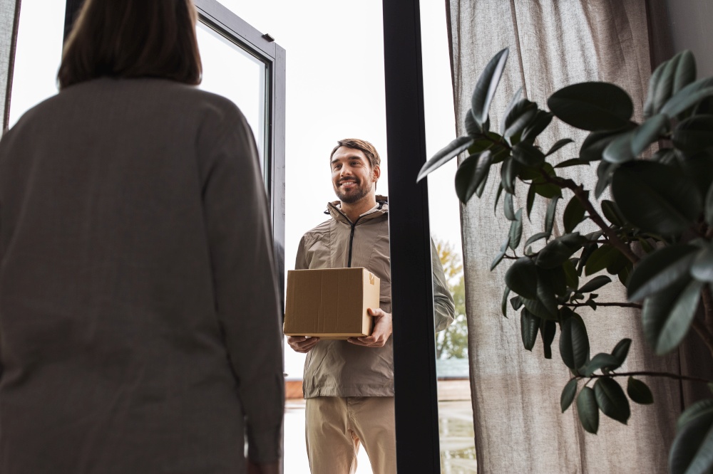 shipping, transportation and people concept - delivery man with parcel box and customer at home. delivery man with parcel box and customer at home