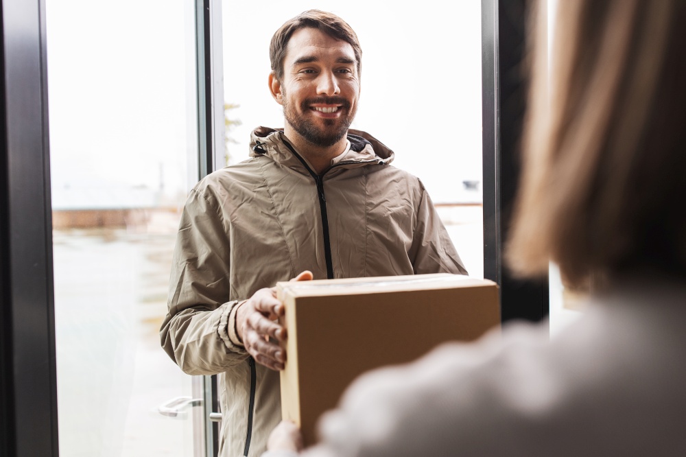 shipping, transportation and people concept - delivery man giving parcel box to customer at home. delivery man giving parcel box to customer at home