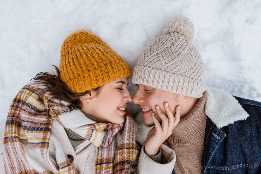people, love and leisure concept - happy smiling couple lying on snow in winter. happy smiling couple lying on snow in winter