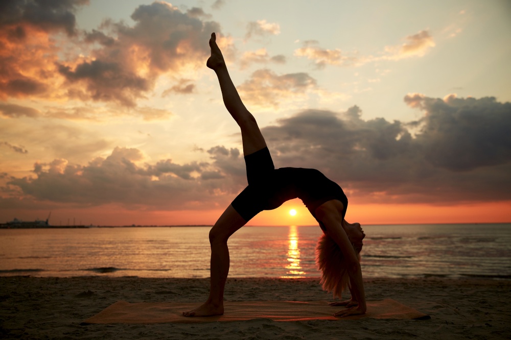 fitness, sport, and healthy lifestyle concept - woman doing yoga bridge pose on beach over sunset. woman doing yoga bridge pose on beach