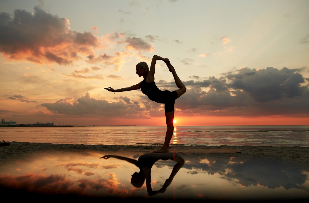 fitness, sport, and healthy lifestyle concept - woman doing yoga dancer pose on beach over sunset. woman doing yoga dancer pose on beach over sunset