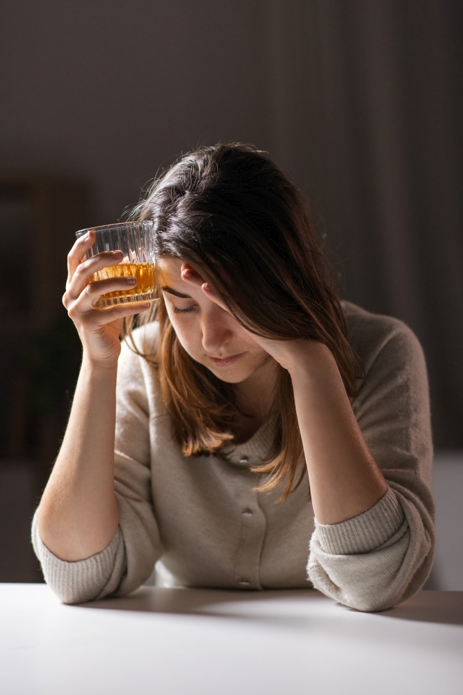 alcoholism, alcohol addiction and people concept - drunk woman or female alcoholic drinking whiskey at home. woman alcoholic drinking strong alcohol at home