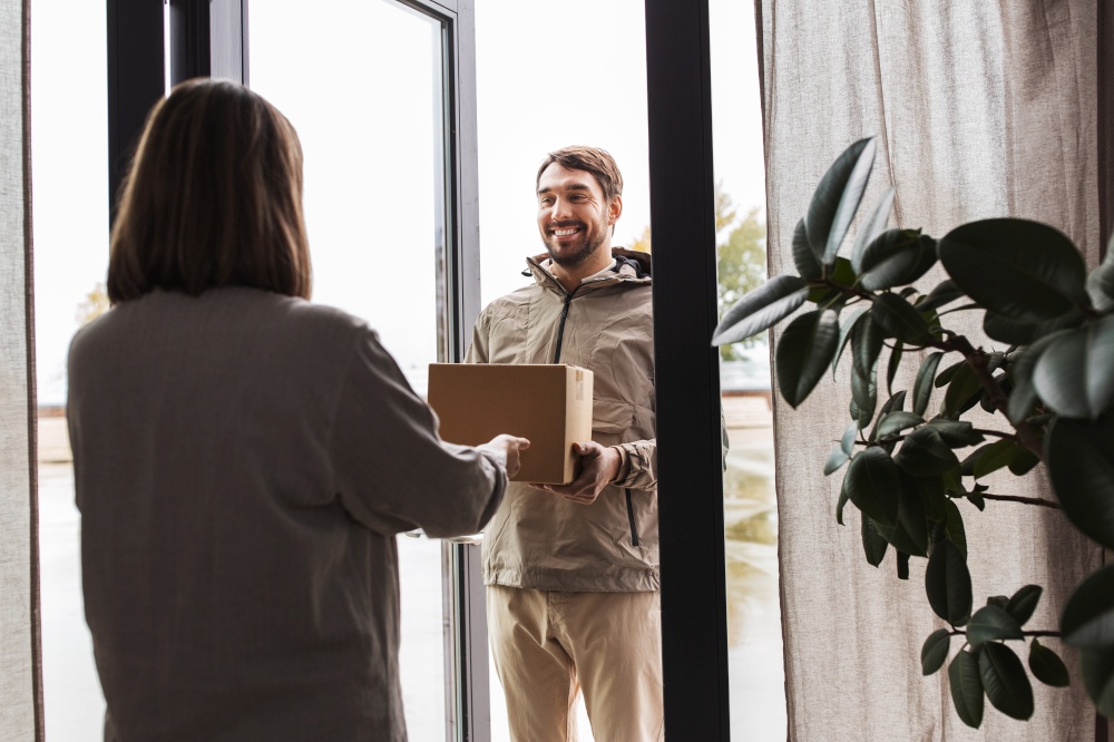 shipping, transportation and people concept - delivery man with parcel box and customer at home. delivery man with parcel box and customer at home