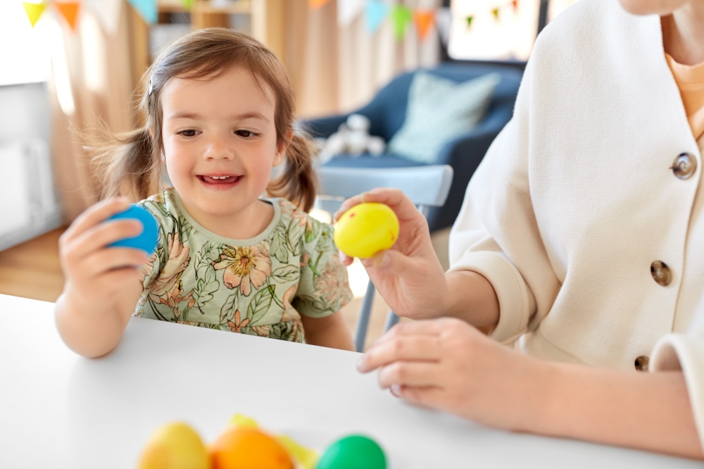 holidays, family and people concept - happy mother and little baby daughter with colored easter eggs at home. mother and child with colored easter eggs at home
