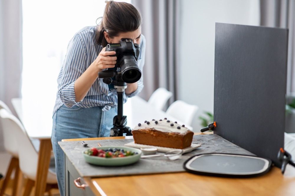 blogging, profession and people concept - female food photographer with camera photographing cake in kitchen at home. food photographer with camera working in kitchen