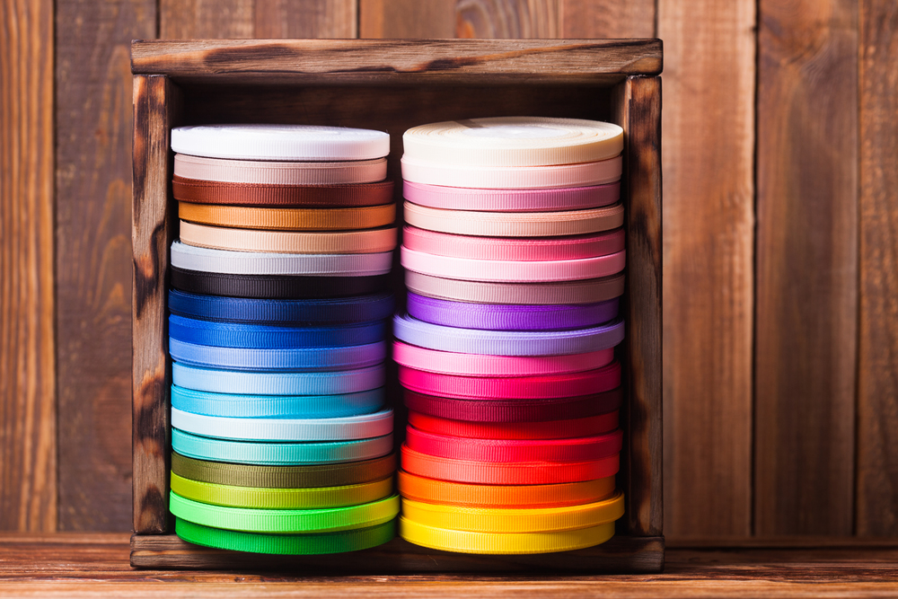 Various colors ribbon bobbins in vintage wooden box. Colorful ribbon bobbins in the wooden box