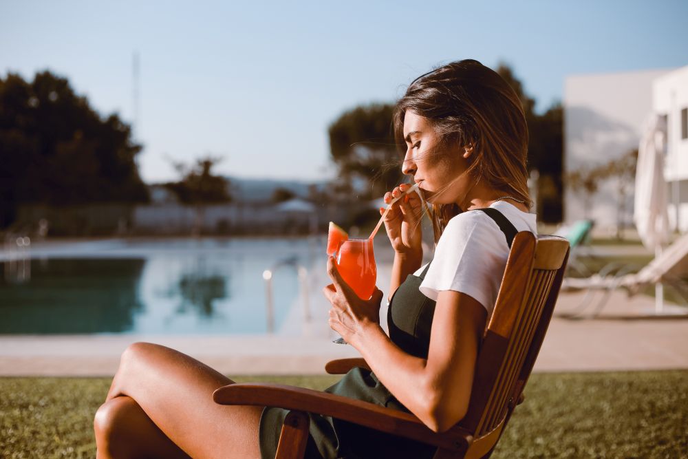 Beautiful woman drinking cocktail near the pool - Spring and Summer