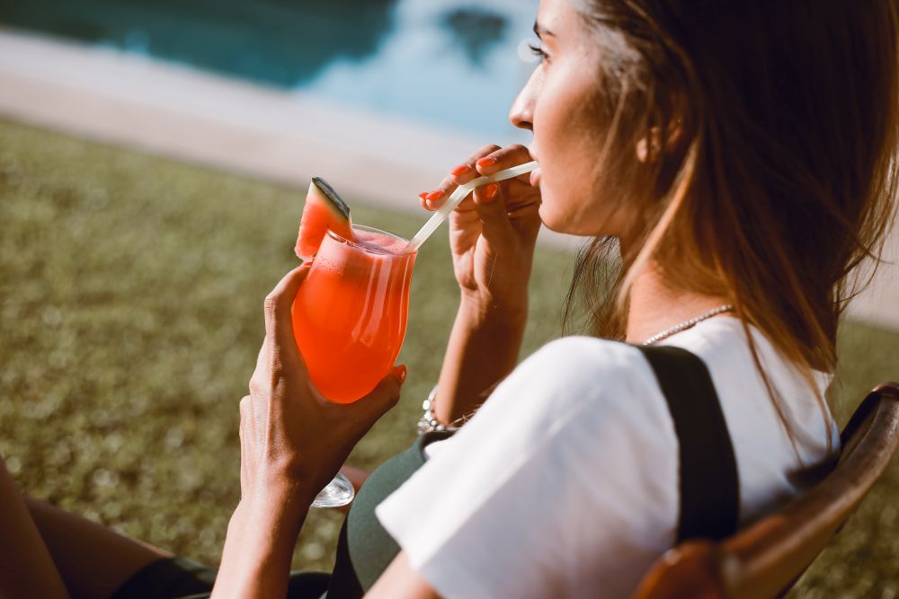 Beautiful woman drinking cocktail near the pool - Spring and Summer