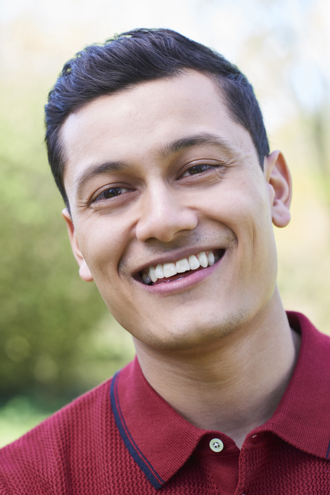 Outdoor Head And Shoulders Portrait Of Smiling Young Man