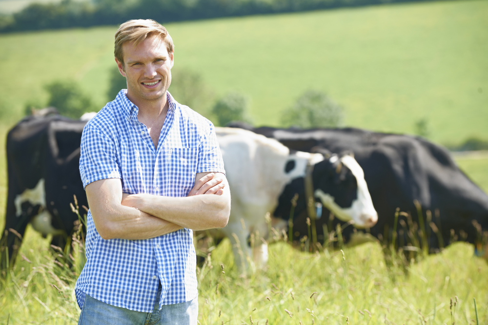Portrait Of Dairy Farmer In Field With Cattle