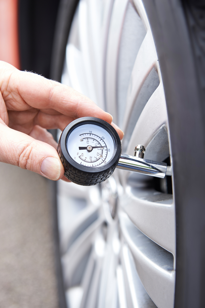 Close-Up Of Man Checking Car Tyre Pressure With Gauge
