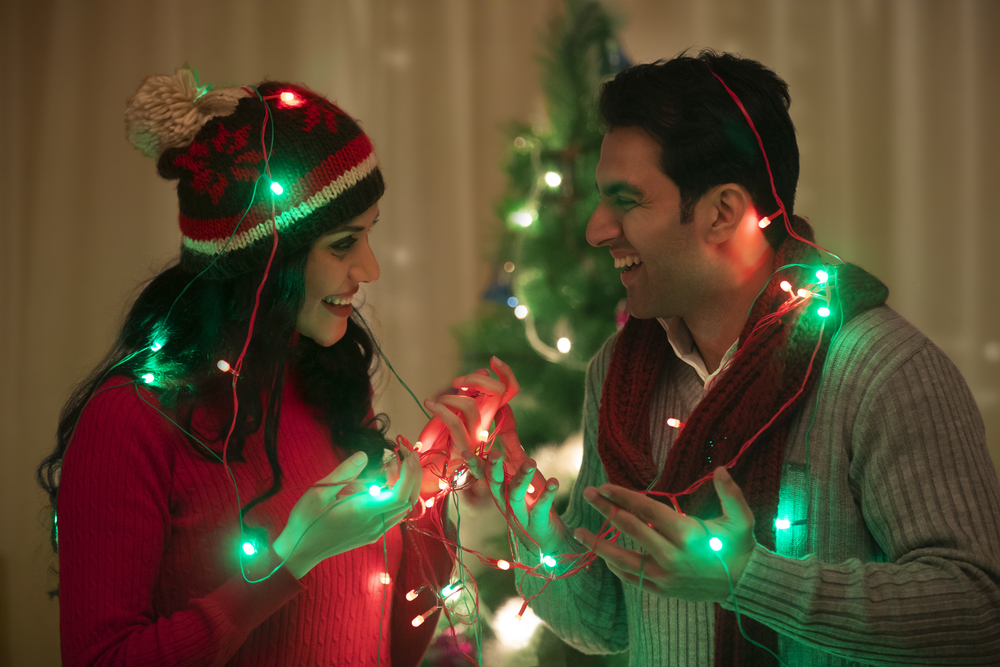 young couple wrapped fairy light at Christmas Celebrations