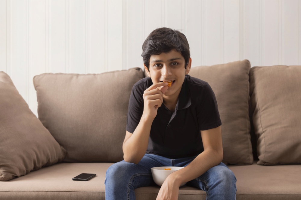A SMART TEENAGER SITTING AND EATING SNACKS AT HOME