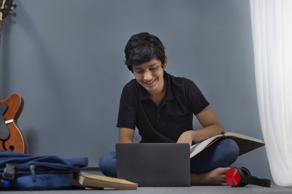A HAPPY TEENAGER SITTING AT HOME AND ATTENDING ONLINE CLASS