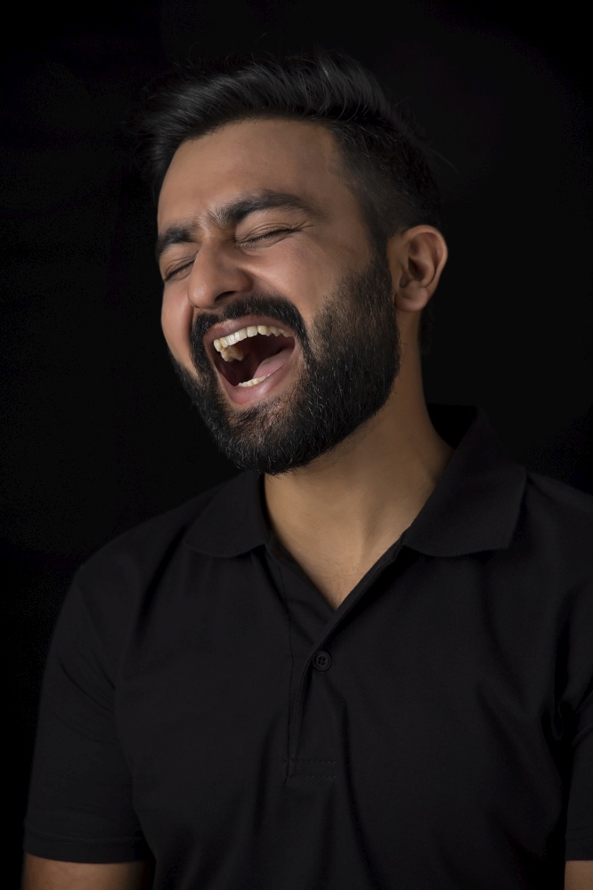 A BEARDED YOUNG MAN HEARTILY LAUGHING