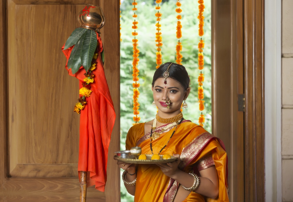 Portrait of a maharashtrian woman in traditional dress celebrating gudi padwa festival holding a pooja plate.