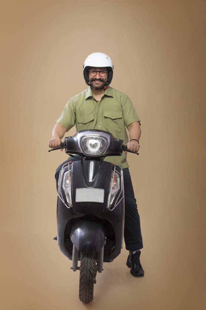 Smiling man sitting on a scooter wearing helmet.