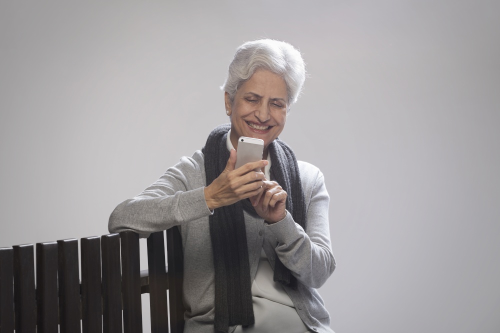 Senior woman in warm clothing using phone