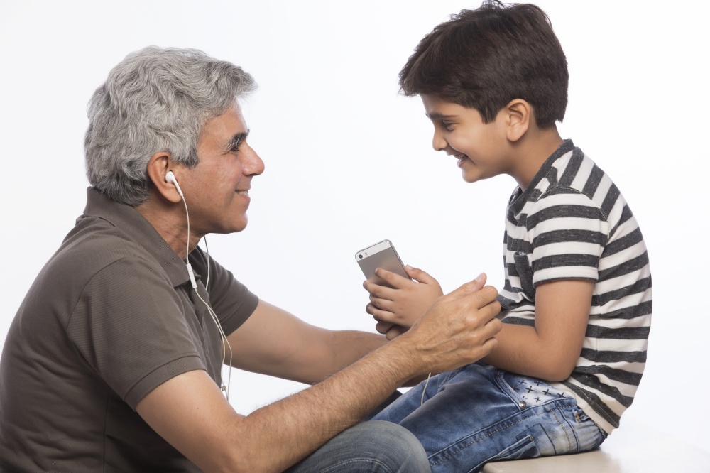 Grandfather and grandson listening to music with earphones