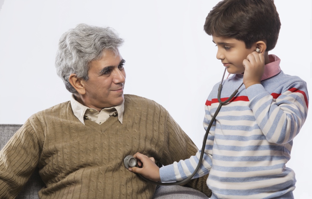 Boy listening to grandfather's heartbeat with stethoscope