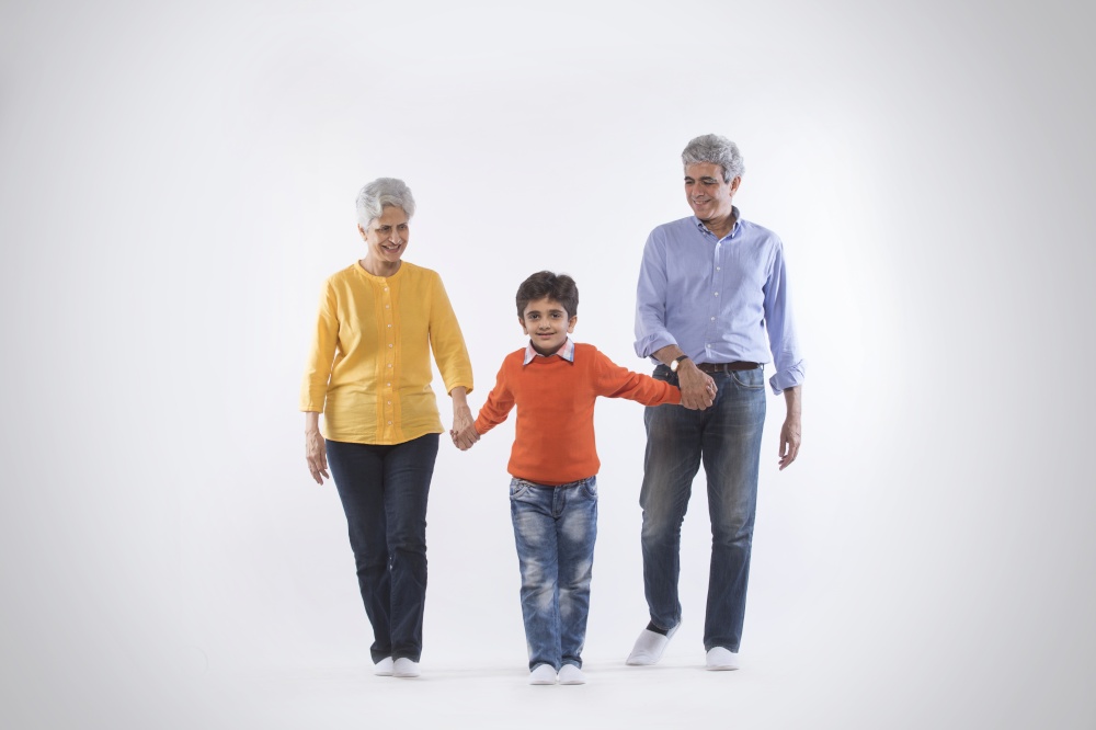 Grandparents holding their grandson's hand and walking