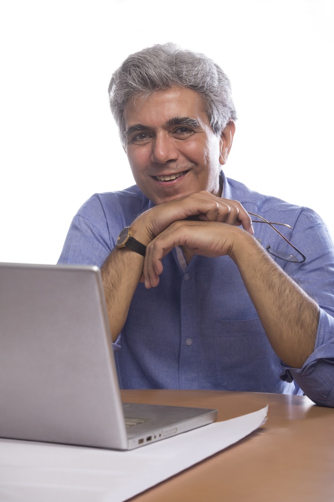 Portrait of senior man sitting at table with laptop