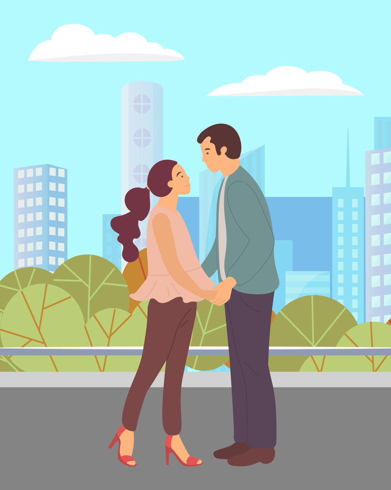Couple walking in a city park. Young guy and girl holding hands, looking into each other s eyes, romantic walk. Lovers man and woman met on a date outdoor. Romantic promenade in the open air. Couple walking in park. Young guy and girl holding hands, look into each other s eyes, romantic walk