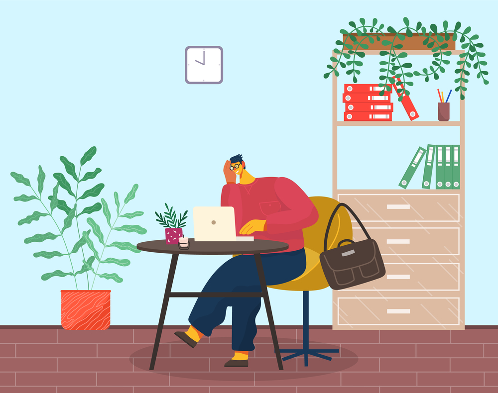 Young pensive man in glasses and red sweater sits, propping face on hand. Yellow armchair, coffee table, laptop, plant, candle. Office cabinet, folders, stationery, climbing plant. Tired man at laptop. Tired or pensive man sits at laptop, briefcase hangs on armchair. Office room with potted plants