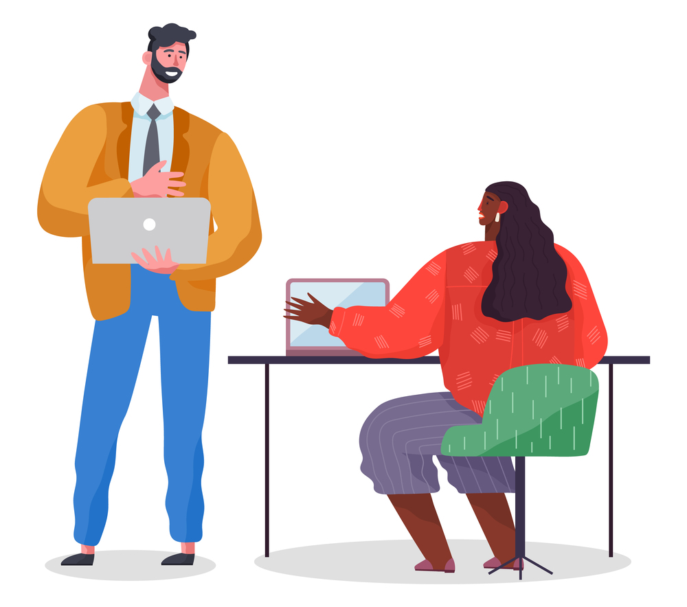 Man in strict suit stands and holds laptop, dark-skinned woman at table with laptop. Office workers at business meeting, discussing project. Coworkers work together. Mutually beneficial cooperation. Business partners in the office, woman and man use laptops. Collaboration, business meeting