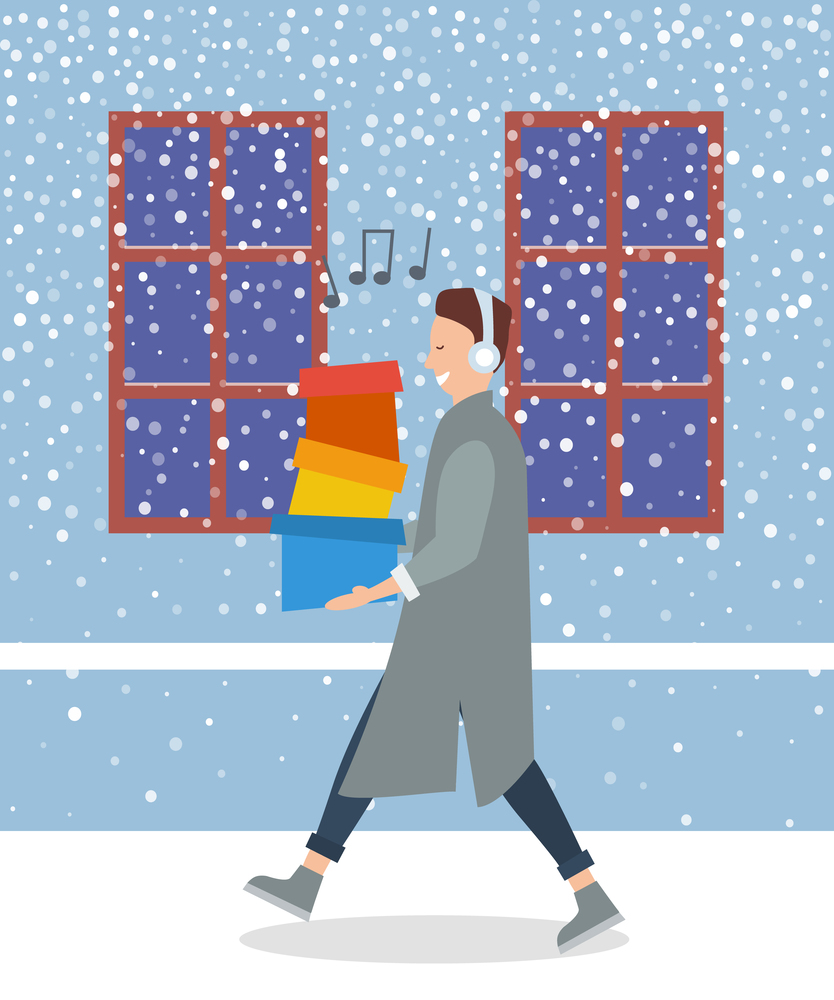 Man is listening to the music. Young handsome fashion shopper guy is singing and holding colorful boxes in his hands. Male character with headphones on his head is walking on the street in winter. Man with shopping boxes walks on the street in winter. Guy with headphones is listening to music