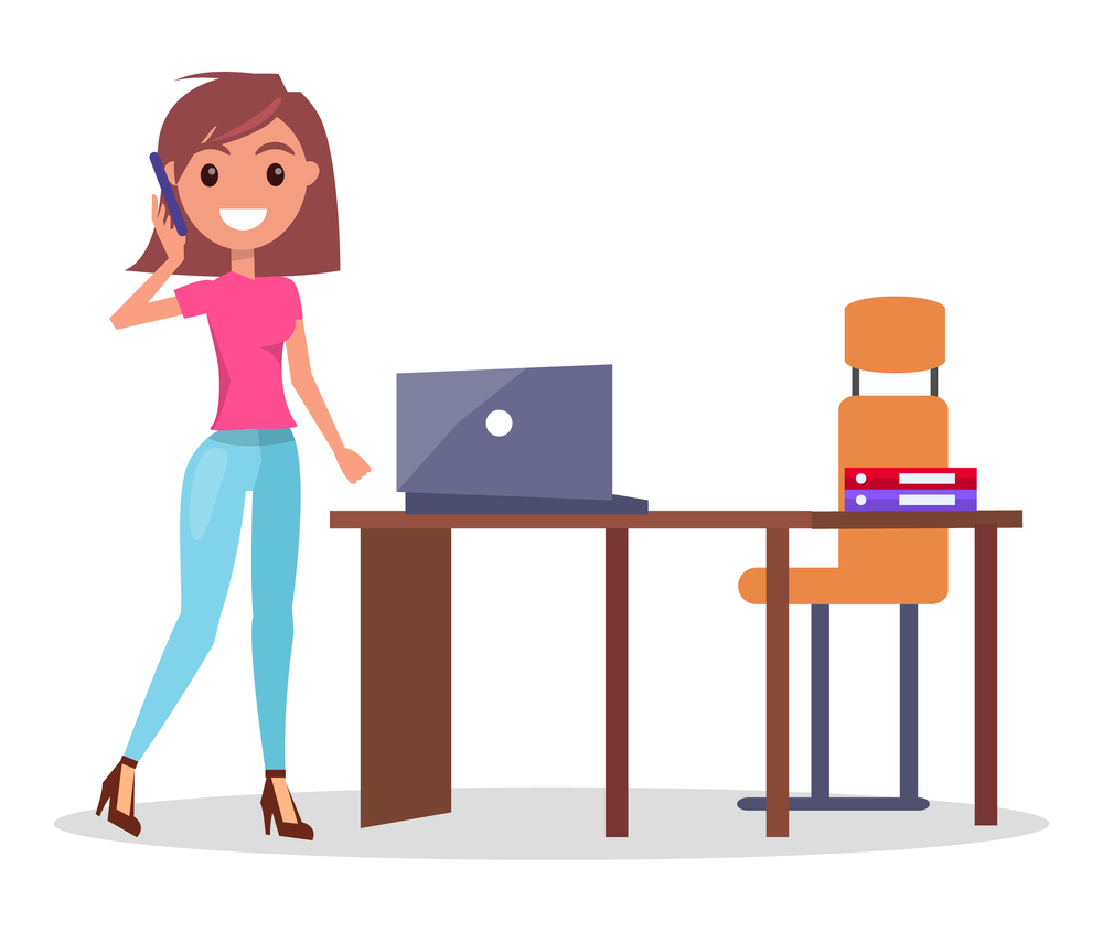 Businesswoman talking by phone standing near office table with laptop and armchair, smiling pretty woman solving business problems, cheerful woman wearing pink t-shirt and jeans using mobile phone. Businesswoman talking by phone standing near office table with laptop and armchair, smiling woman