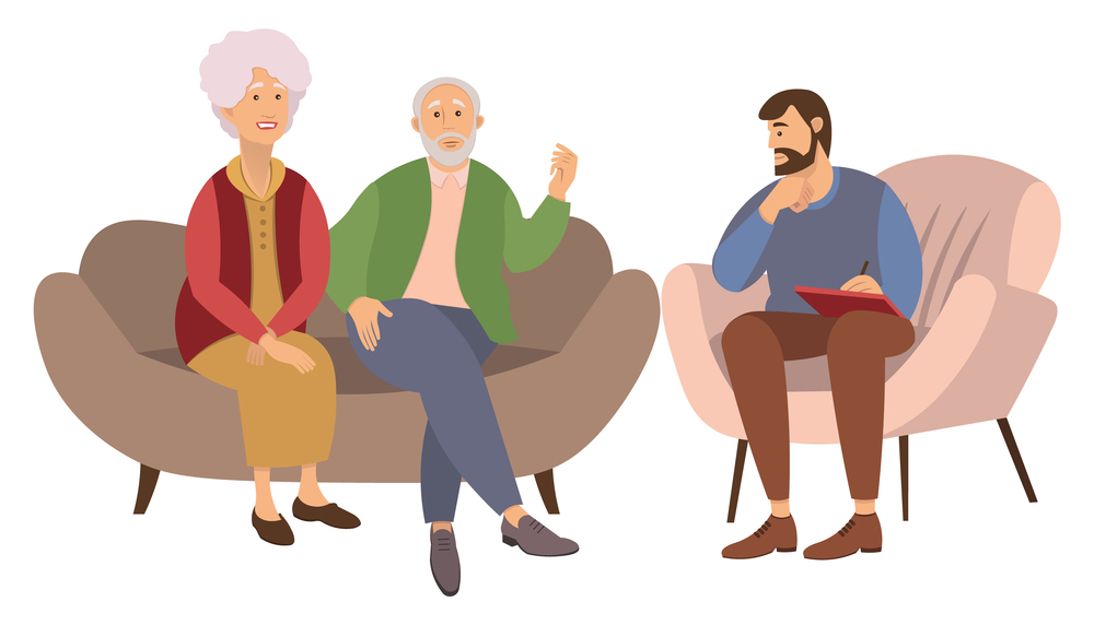 Old man and woman are sitting on a large brown sofa. The psychologist is sitting with a paper and asking questions. Married couple sitting on the couch together with happy psychotherapy session. A man and a woman are sitting on a large sofa. The psychologist sits with a tablet and asks