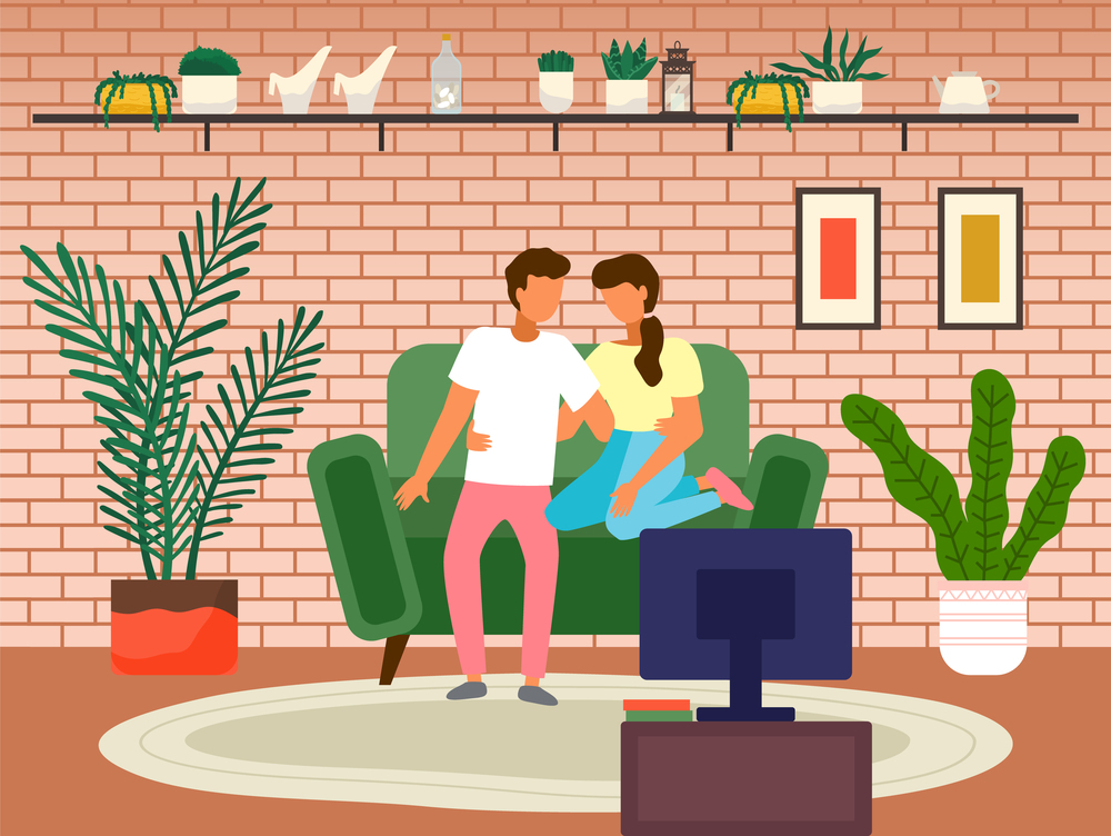 Couple watching television in the living room interior. Family stay at home. Man and woman sitting on the couch hugging each other watching a romantic movie. Young family spend time together. Couple watching television in the living room interior. Man and woman sitting on the couch hugging