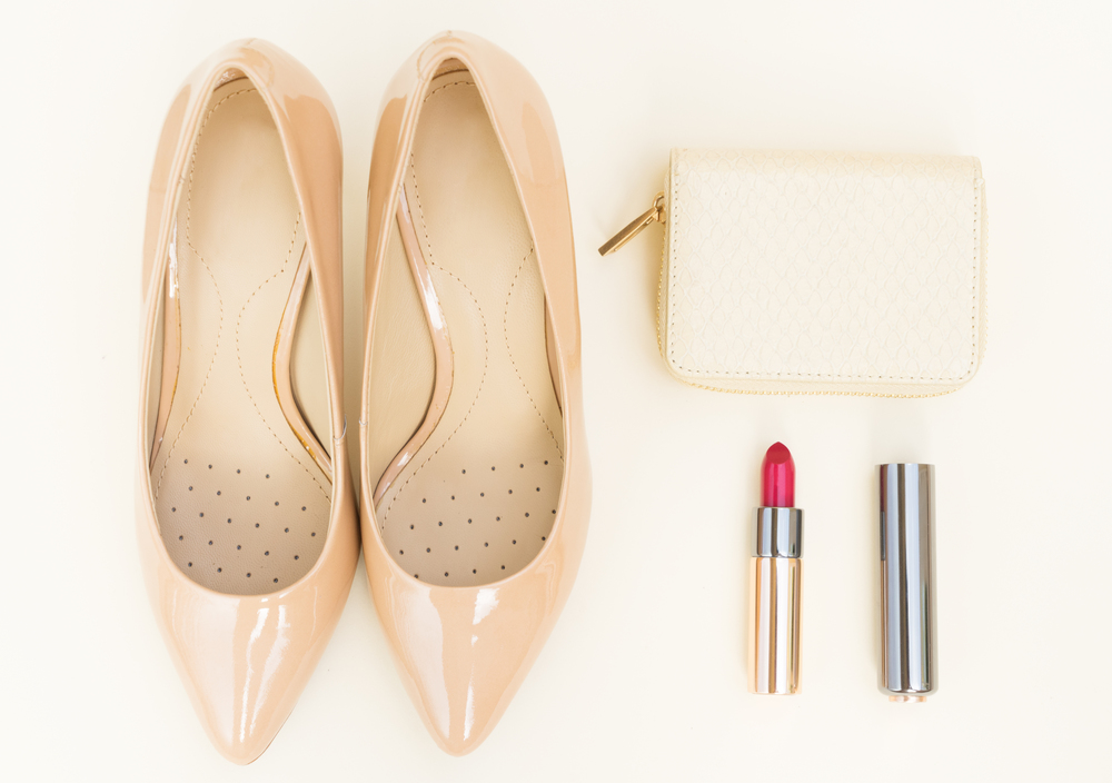 Nude colored high heels still life with wallet and red lipstick. Nude colored high heels still life