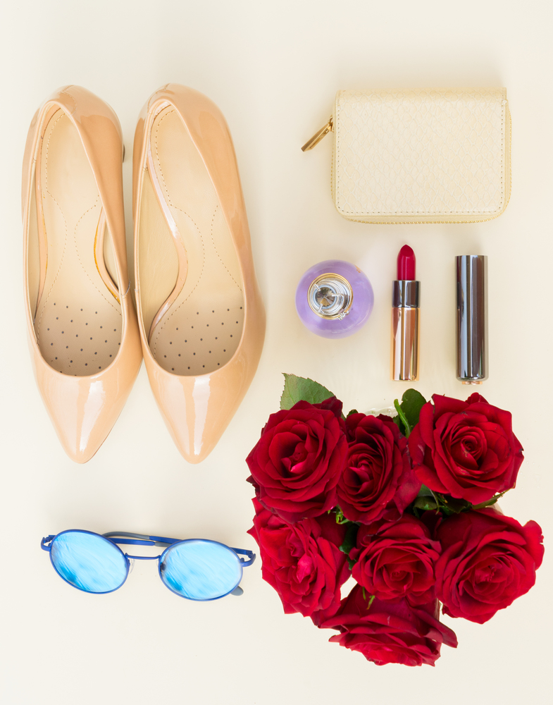Nude colored high heels still life with wallet, roses, sun glasses and red lipstick, top view. Nude colored high heels still life