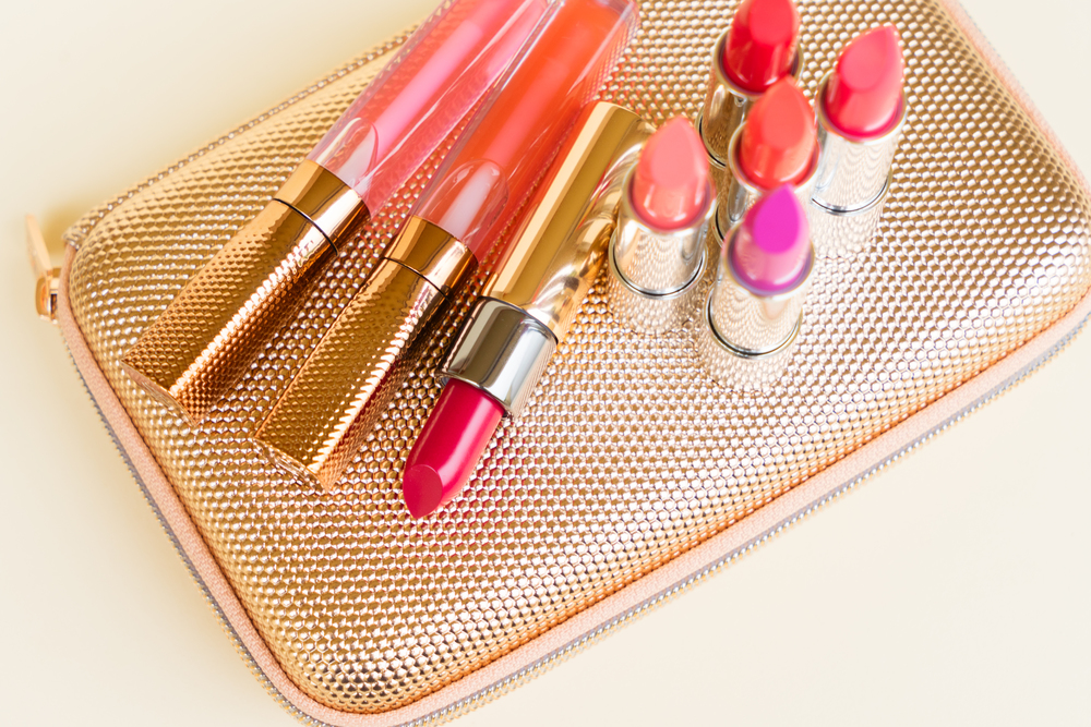 Collection of colorful lipsticks on golden woman pursue bag close up. Collection of lipsticks