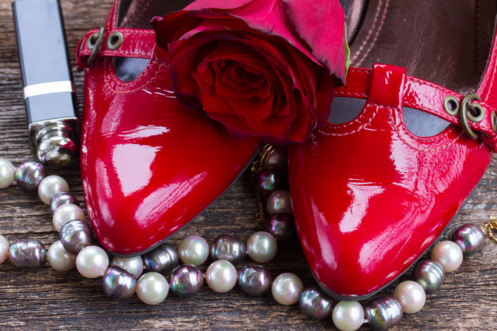 pair of red shoes with rose flower and pearl jewellery . red shoes with rose flower
