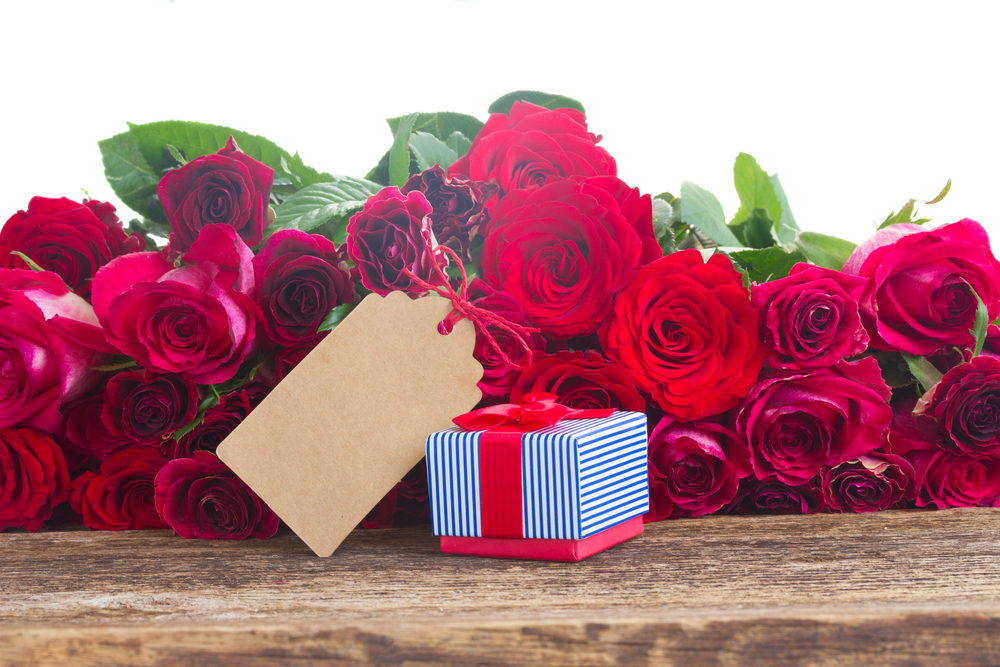 red and pink  roses  with gift box and paper note on wooden table border  isolated on white background. Border of red roses