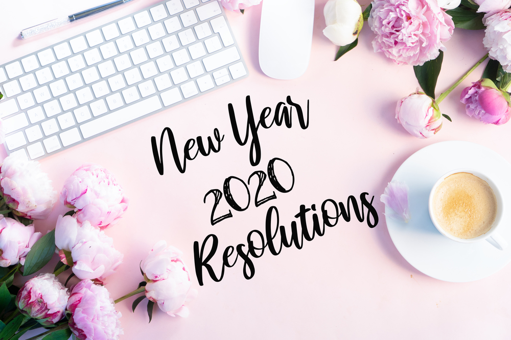 New 2020 year resolutions modern keyboard with female accessories and fresh peony flowers, copy space on pink background. Top view home office workspace