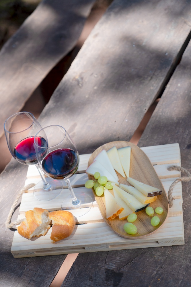 picnic with glasses of red wine, bread and cheese, shadow overlay over table. picnic with wine