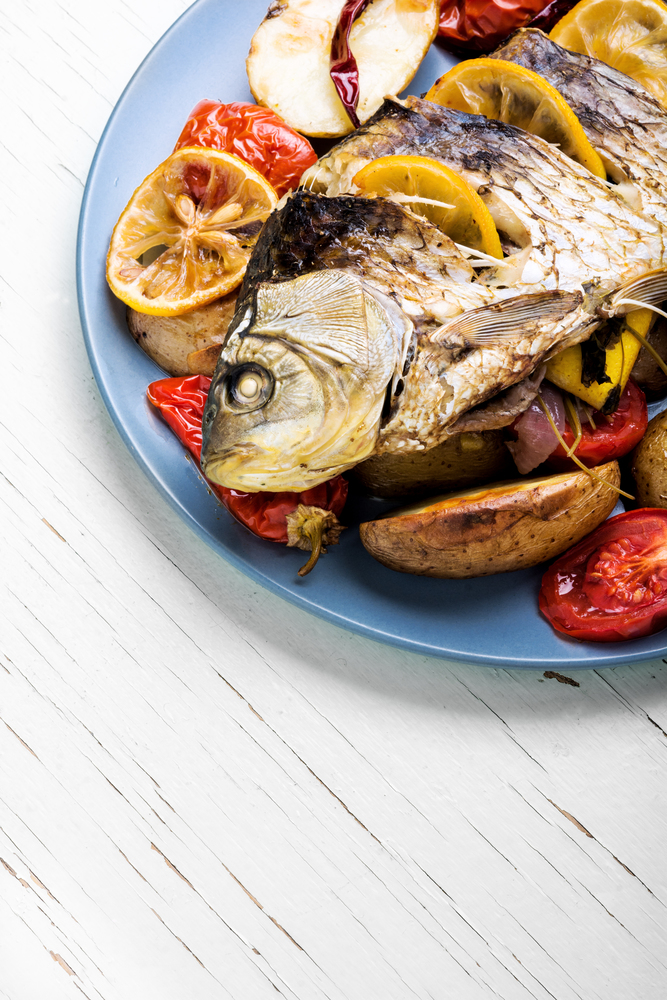 delicious roasted fish with lemon and garnish. fish baked with vegetable garnish