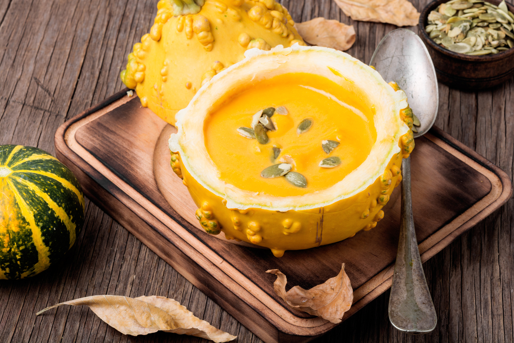 Vegetarian pumpkin cream soup with seeds in pumpkin.Seasonal autumn food.Cream soup in pumpkin. Autumn pumpkin soup