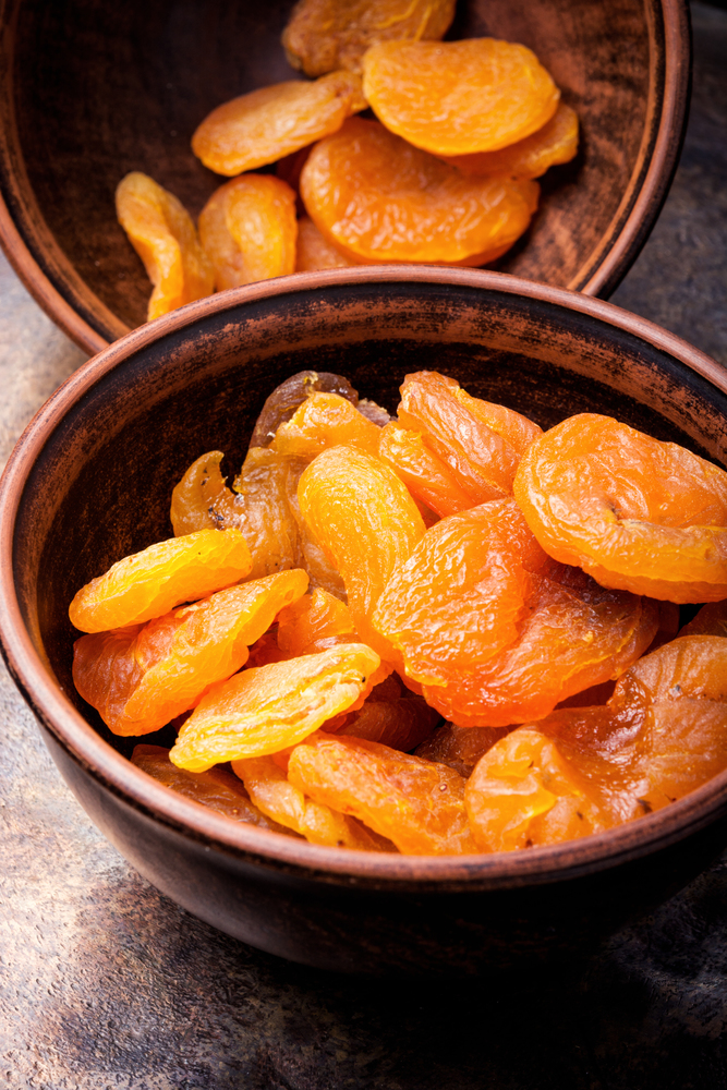 Delicious dried apricots in bowl on retro background. Heap of dried apricots