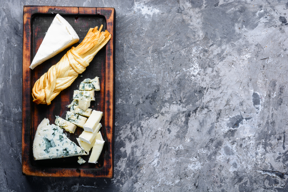 Cheese on dark slate on background.Different sorts of cheese.Various types of cheese. Assortment of cheeses