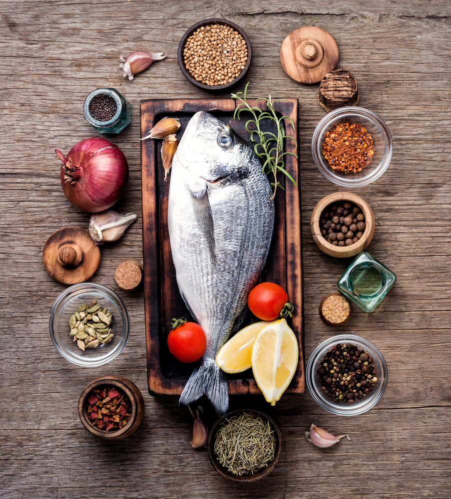Fresh fish with ingredients for cooking.Fresh dorado fish on wooden cutting board. Fresh fish with spices