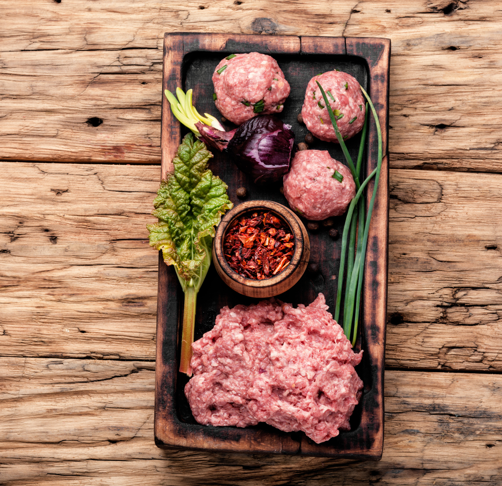 Fresh raw minced beef on cutting board and ingredients. Raw minced meat