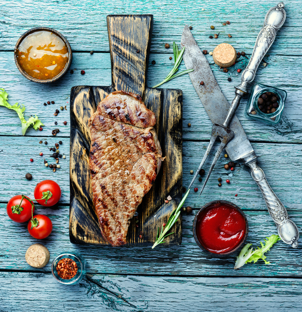 Grilled beef steaks with spices on wooden cutting board.Succulent grilled steak. Beef steak on a wooden background