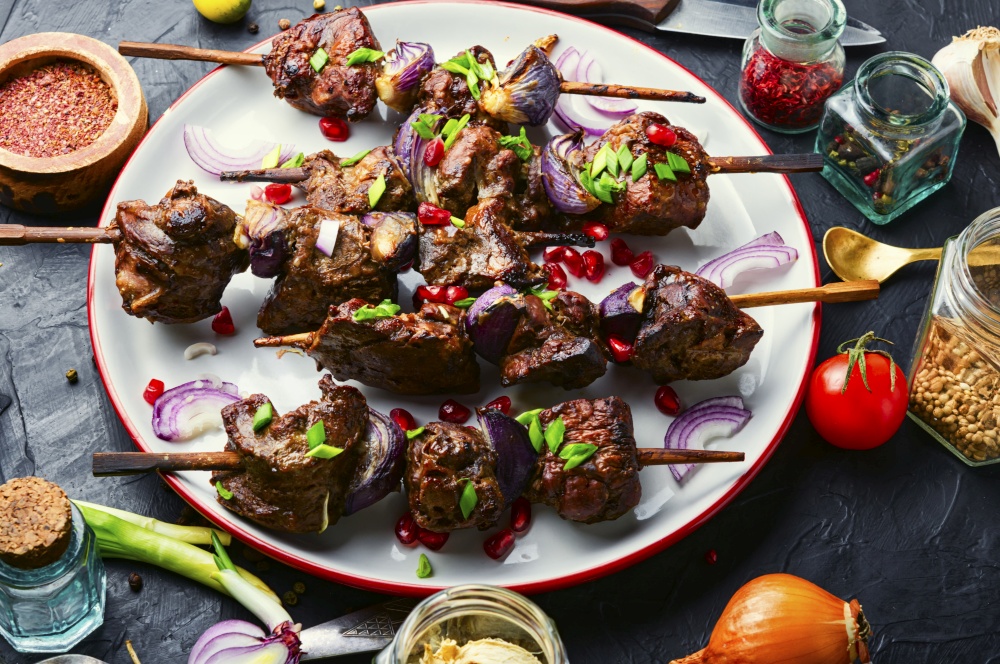 Grilled liver kebab with onion on wooden skewers. Delicious liver kebab