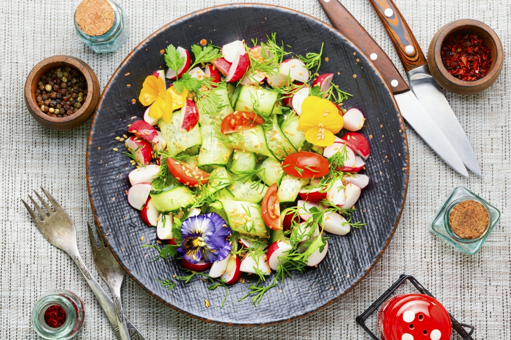 Spring salad with various vegetables and edible flowers. Diet food.Spring vitamin salad. Seasonal vegetable salad