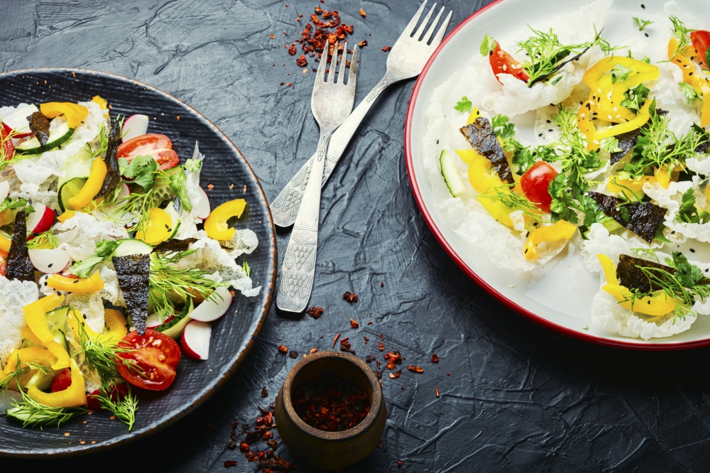 Spring fresh vegetable salad on rice paper.Vegetarian spring salad. Vegetable salad decorated with rice paper